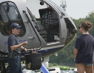 Two women engaging with a police helicopter during a public safety demonstration, highlighting community outreach and emergency response training.
